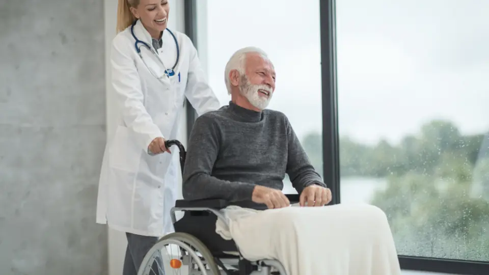 Tekerlekli sandalyedeki yaşlı adama eşlik eden doktor